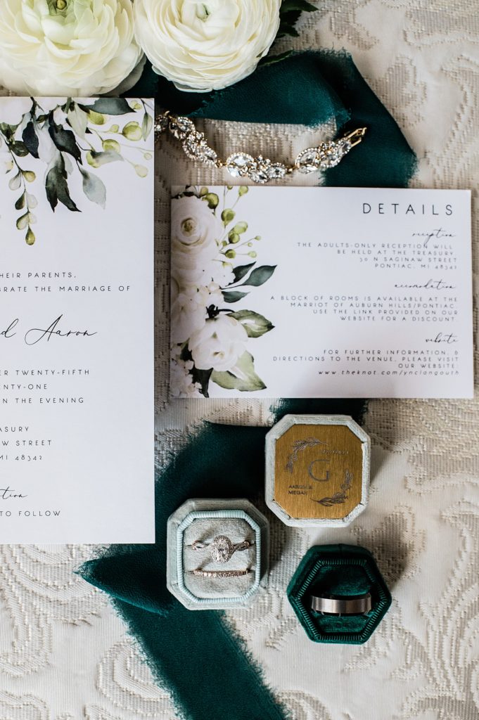 Lay flat image of wedding details in dark teal and off white.