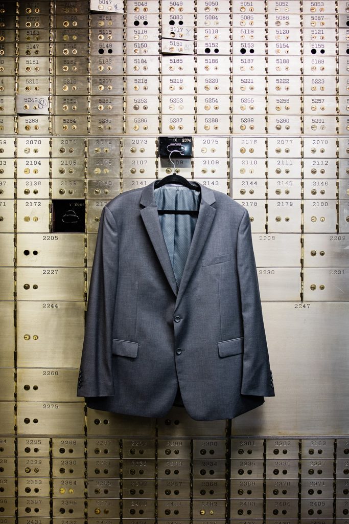 Grooms suit hanging on an old banking wall with metal safe boxes for a Pontiac, Michigan. | Wedding at The Treasury Pontiac, Michigan