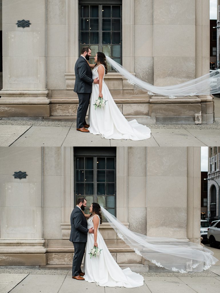 Bride and groom embracing on a street corner, with her veil flying in the wind at their Pontiac wedding.