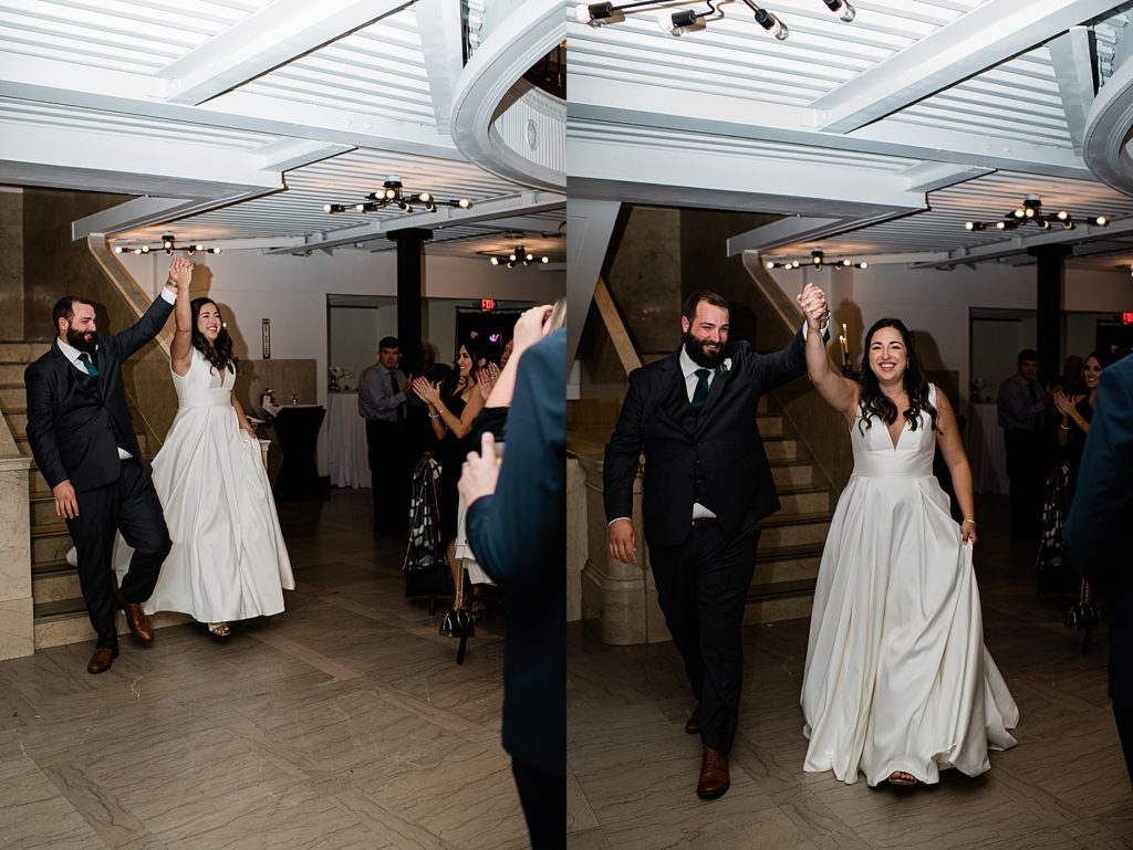 Bride and groom entering their reception with hands clasped in the air. 