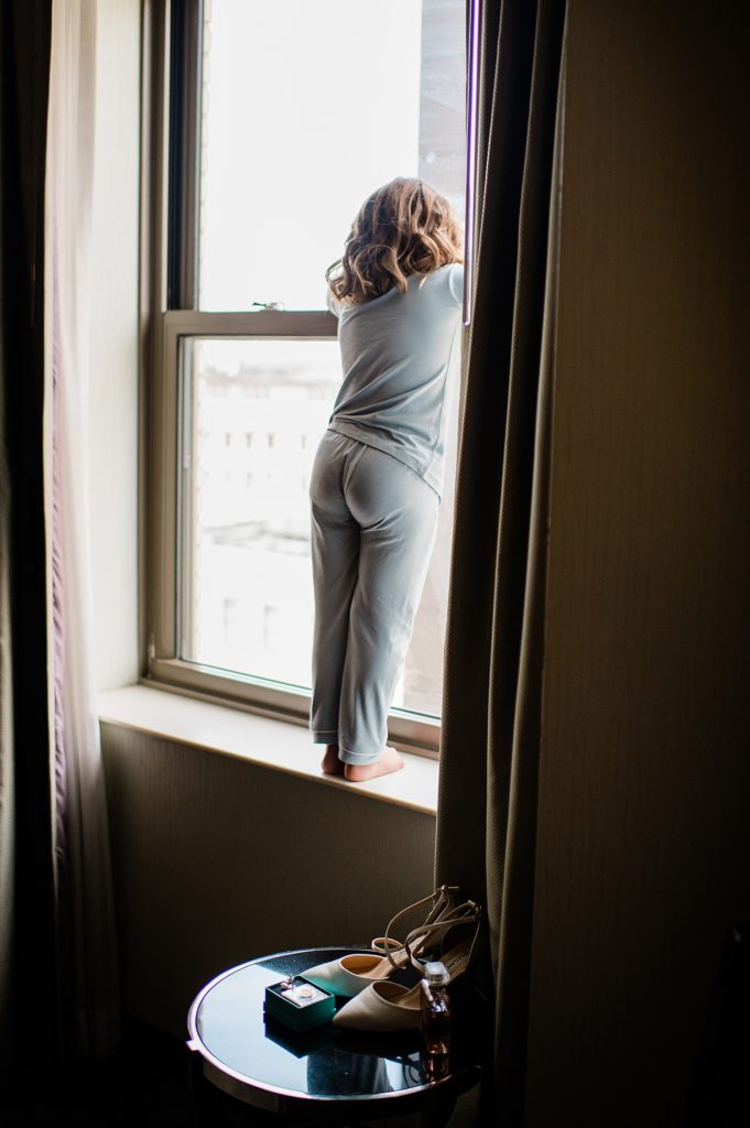 Small girl stands in a hotel window looking out the glass.