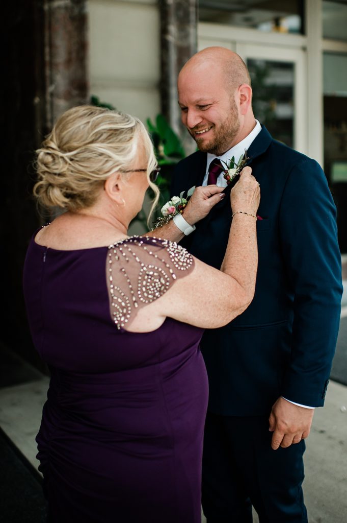 A groom having his boutonnière fastened by his mother. 