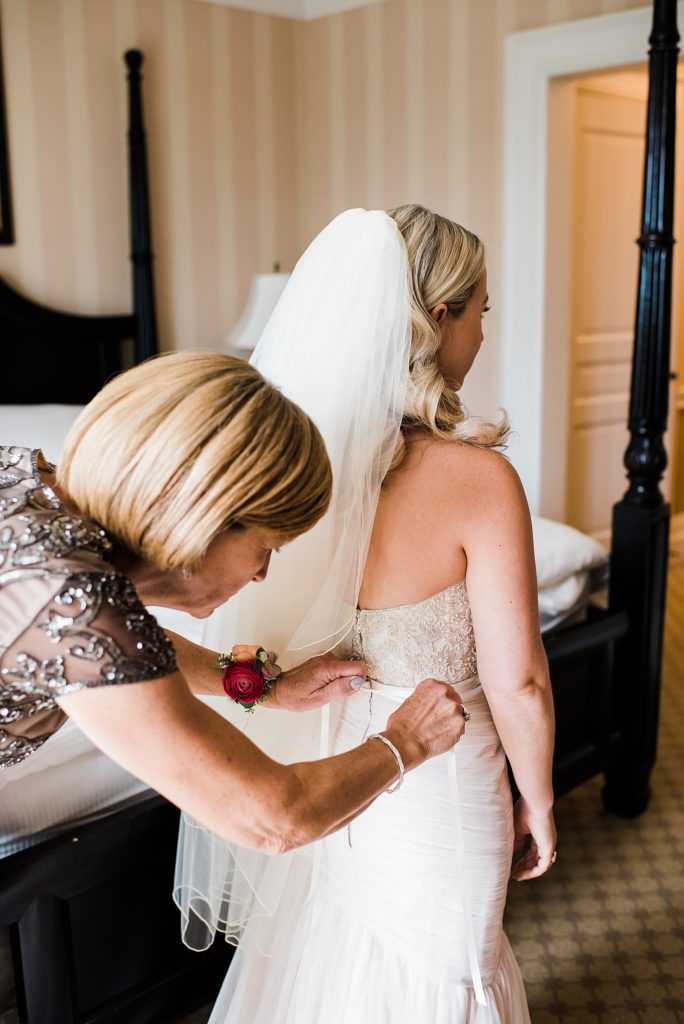 Bride getting her dress buttoned by her mother before the wedding.