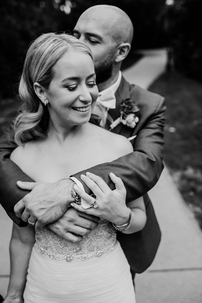 Black and white image of bride and groom all wrapped up in an embrace. 