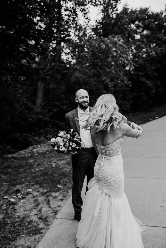 Black and white image of a bride and groom dancing on a sidewalk. 