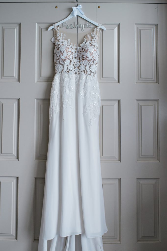 Lace wedding gown hanging on a closet door. 