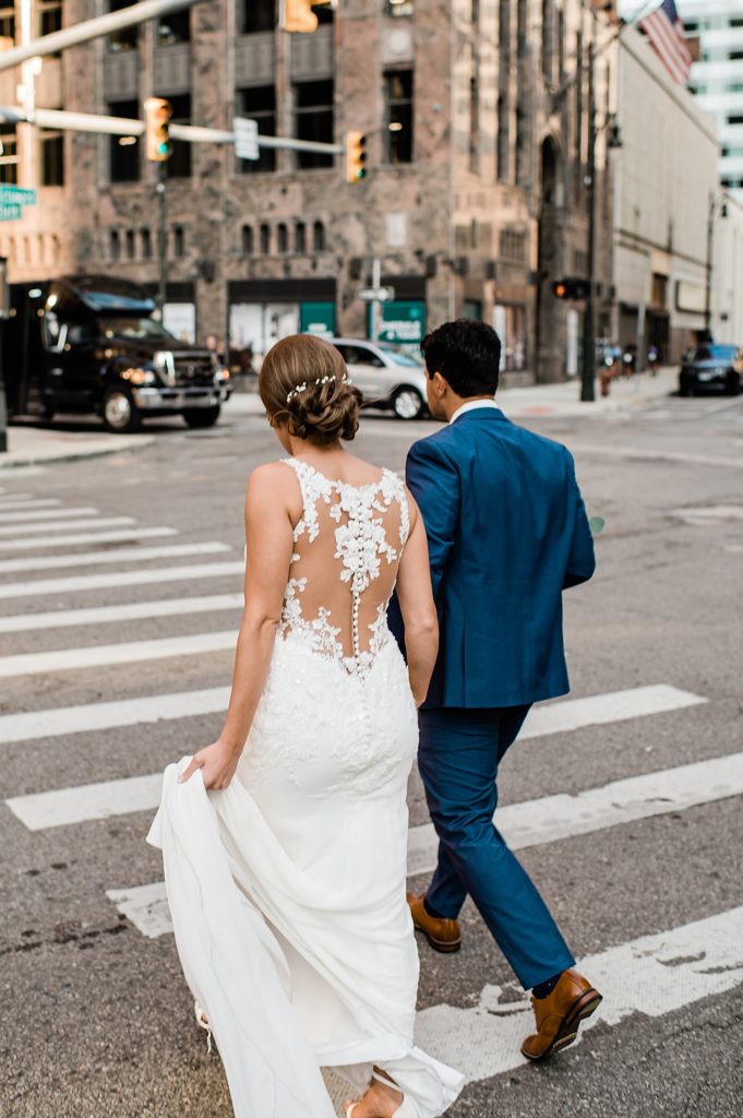 Bride and groom crossing a cross walk in a busy city. 