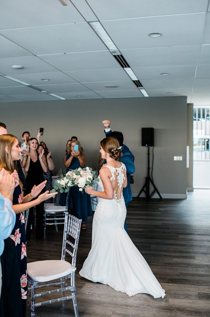Bride and groom entering their reception, groom fist pumping in the air. 