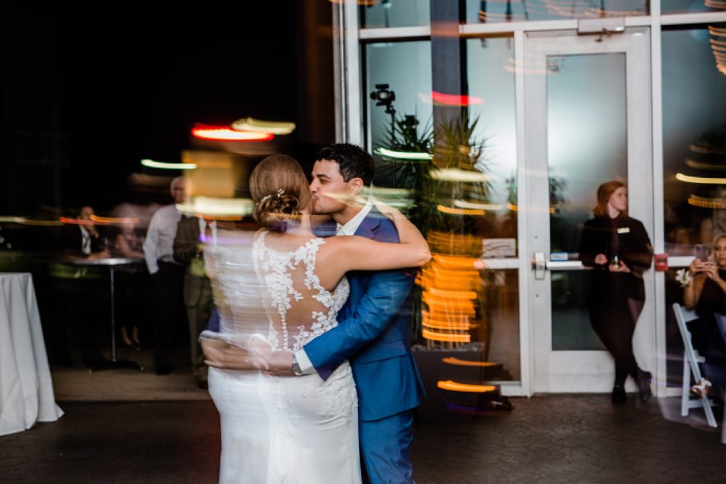 Blurry photo of bride and groom dancing with lights in the background at their Waterview Loft Wedding.