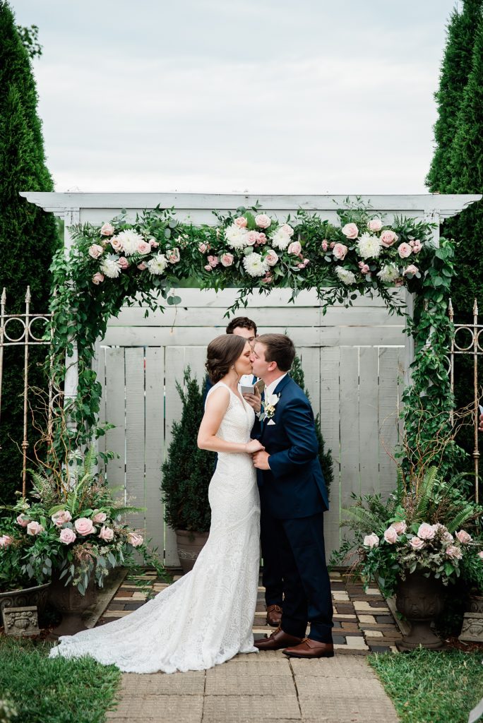 Bride and groom share a kiss at their garden ceremony. 
