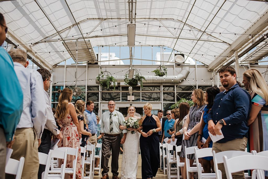 Bride walking down the aisle at her greenhouse ceremony at Downtown Market in Grand Rapids.