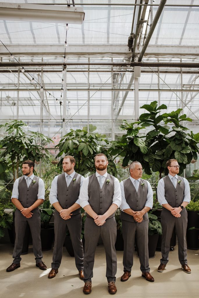 Groom and groomsmen posed in front of fig leaf tree at Downtown Market in Grand Rapids.