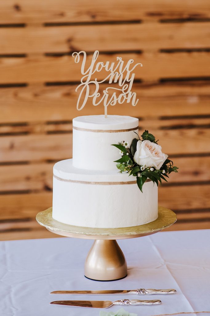 White wedding cake with a topper that says "You're My Person". 