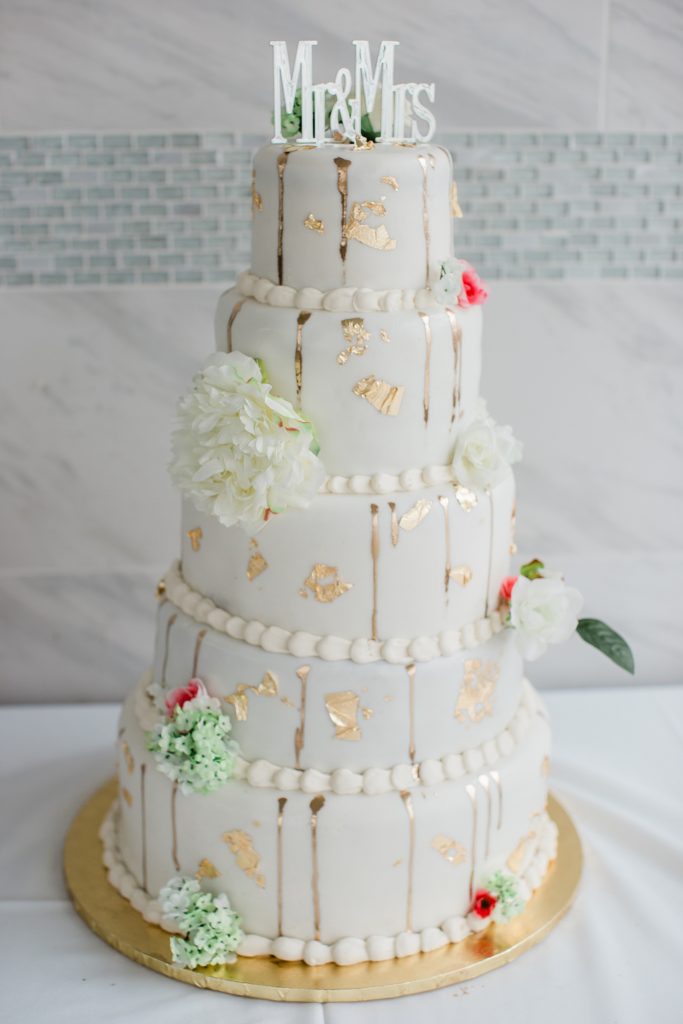 Tall four tier wedding cake with gold flecks on it. 