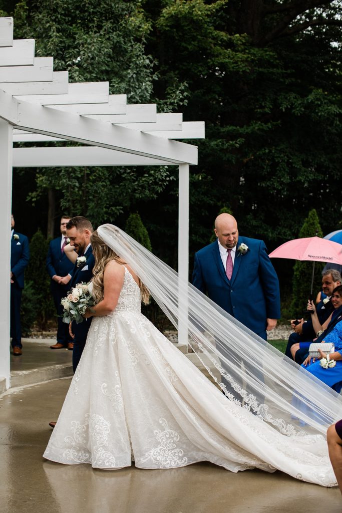 Bride approaching the alter at this outdoor rainy wedding ceremony.