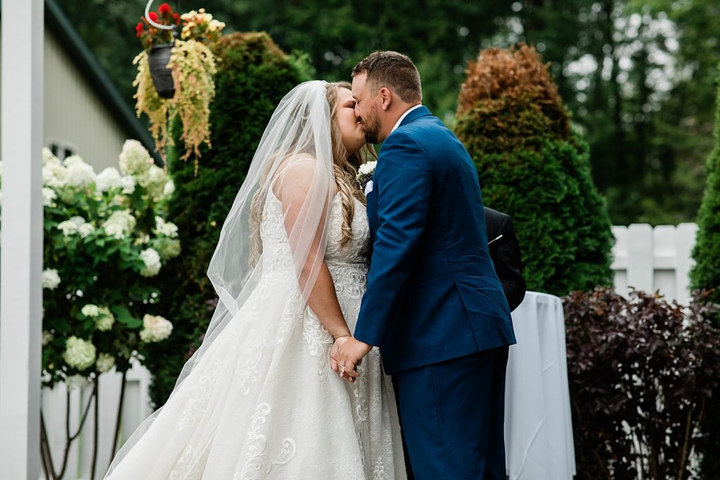 Bride and groom sharing a first kiss at their outdoor ceremony. 