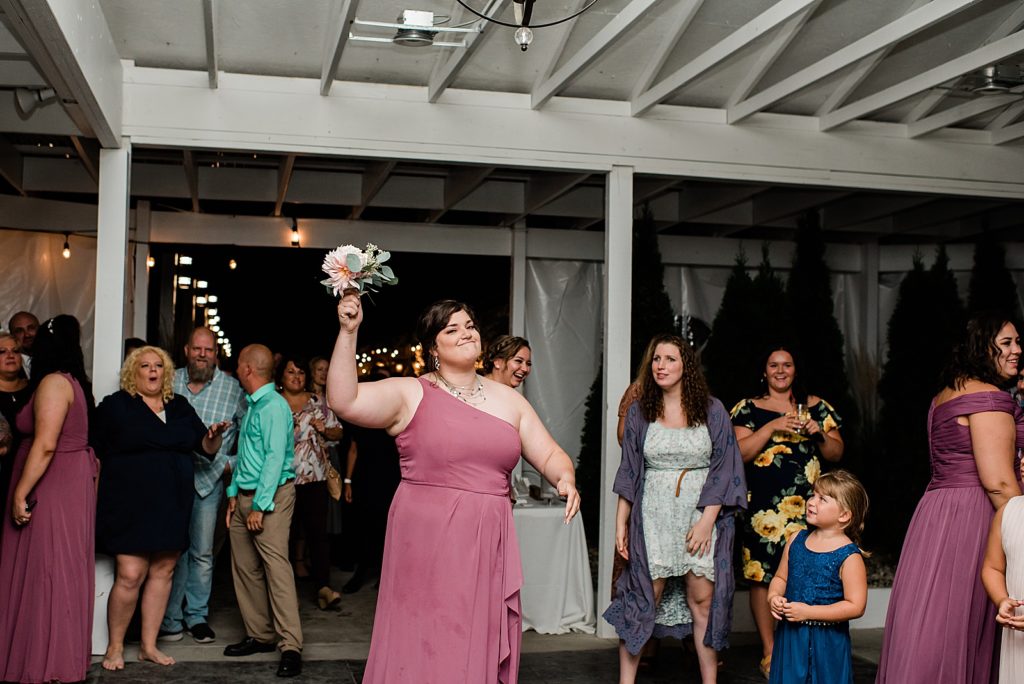Bridesmaid who caught the bouquet showing it off to the camera. 