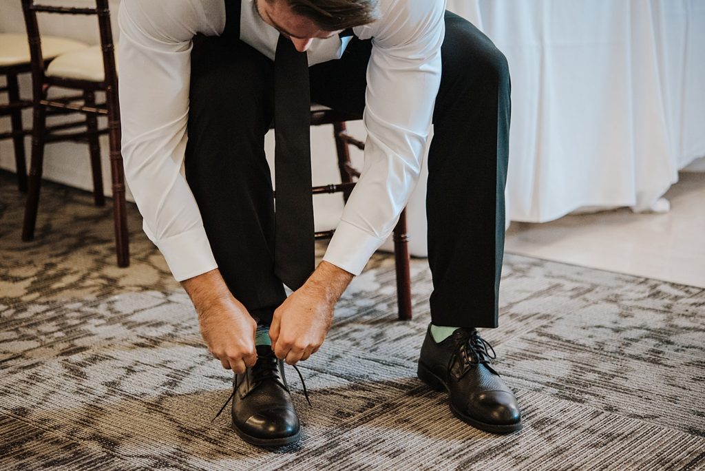 A groom leaning down to tie his shoes. 