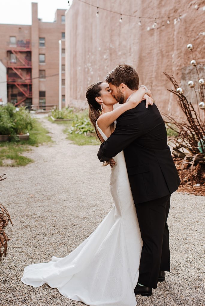 Bride and groom kissing with buildings in the background. 