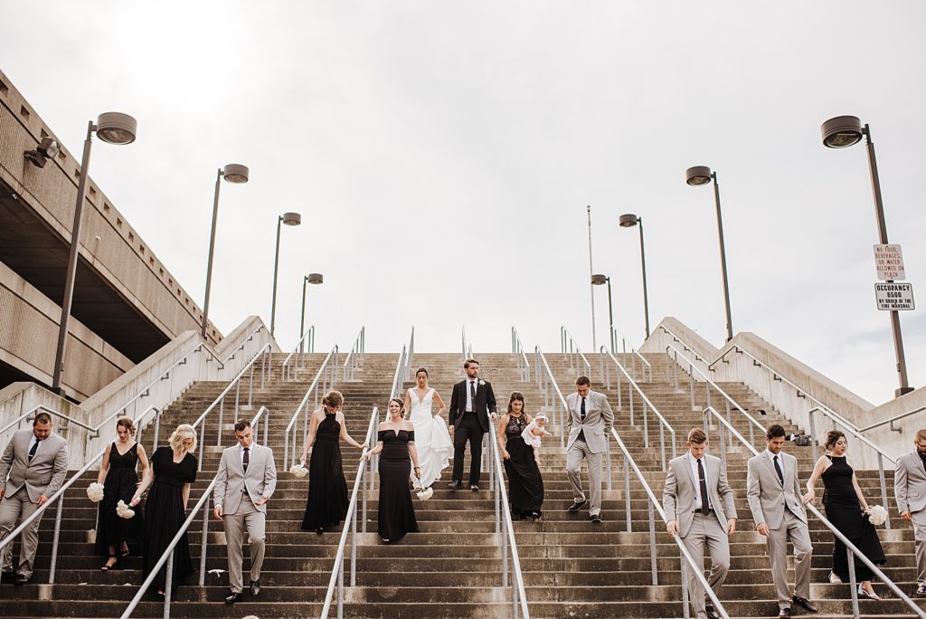 Large wedding party walking down expansive outdoor staircase. 