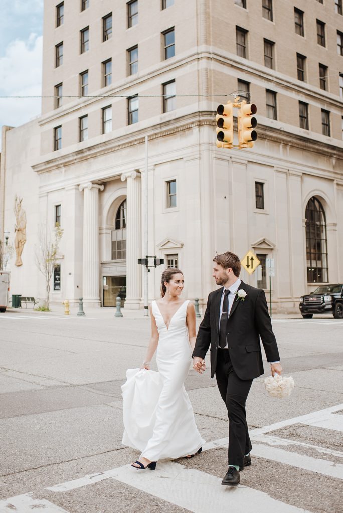 Bride and groom walking across a sidewalk in Pontiac. 