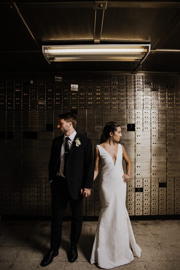 Bride and groom posing in front of historic bank vault at The Treasury wedding venue. 