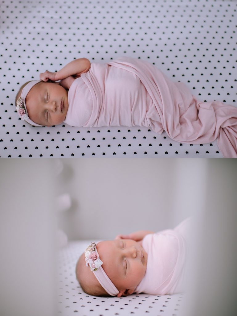 New baby girl in her crib, all wrapped in pink with a pink headband for her newborn photo shoot. 