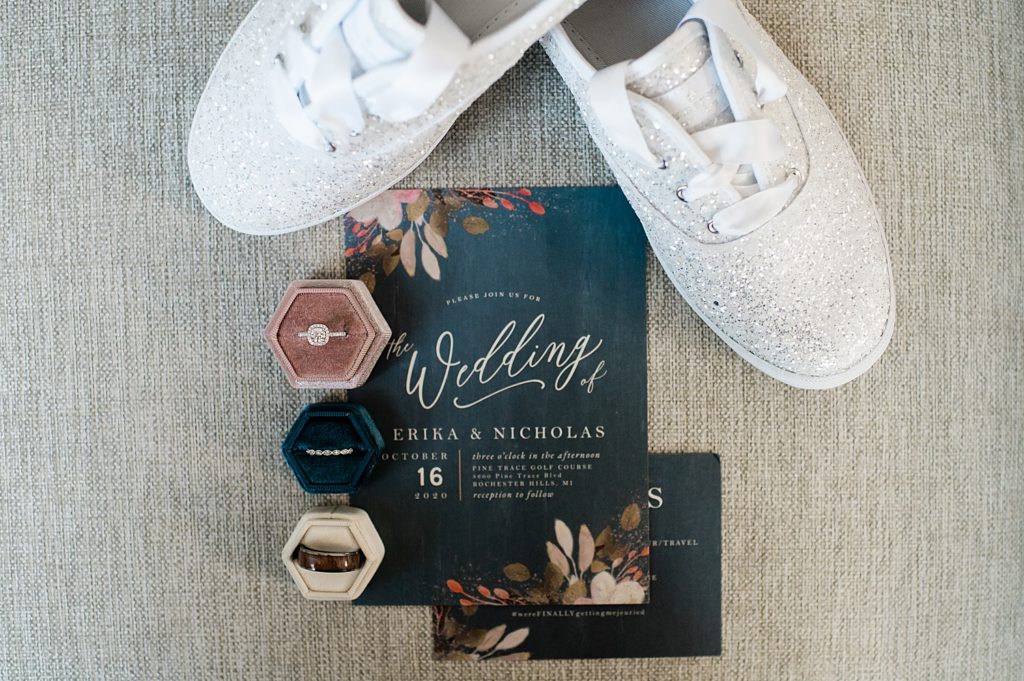Flat lay of wedding details with an invitation and rings by Michigan wedding photographer, Brittany Emerson.