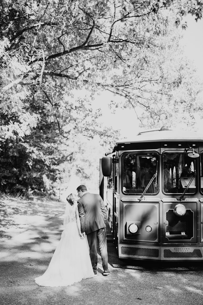 Bride and groom kissing next to an old fashioned trolley at their first look.