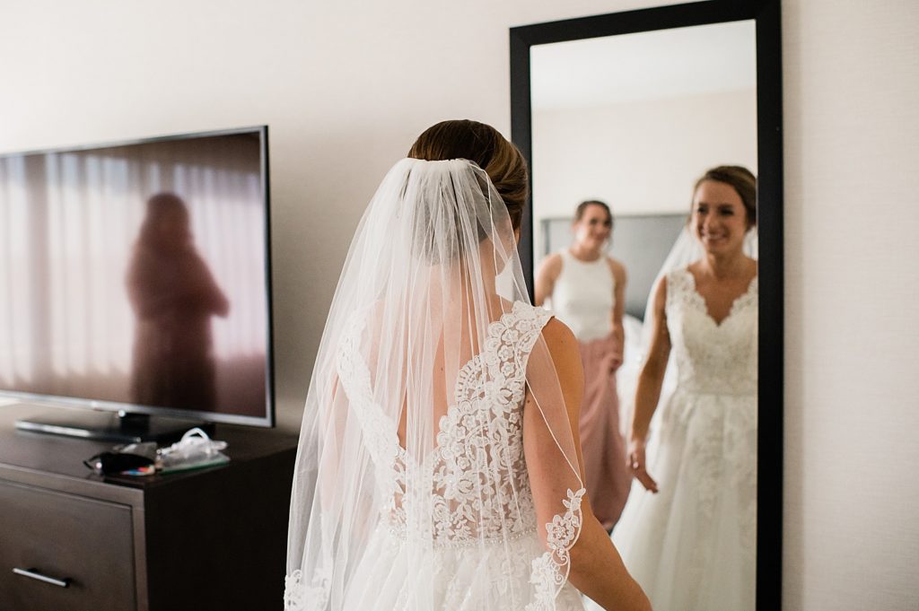 Bride looking at herself in the mirror with her veil on, shot by Michigan Wedding Photographer Brittany Emerson.