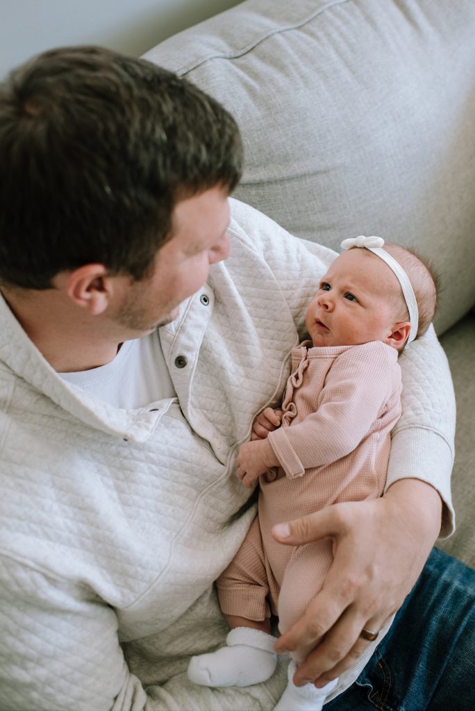 Father holding newborn daughter at photo session with Michigan photographer. 
