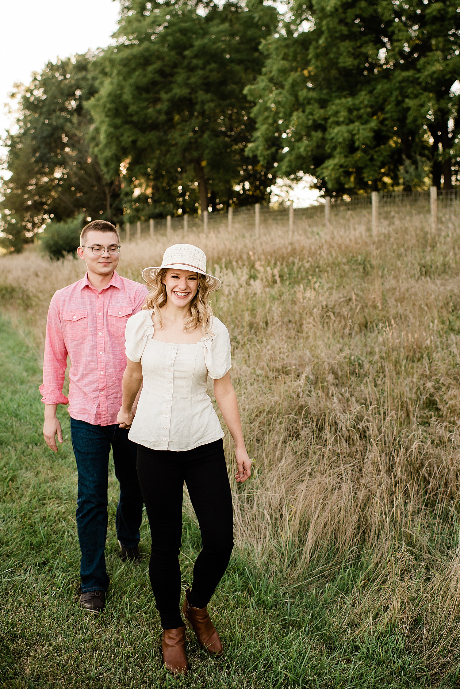 happily engaged couple wearing white hat in park in Michigan