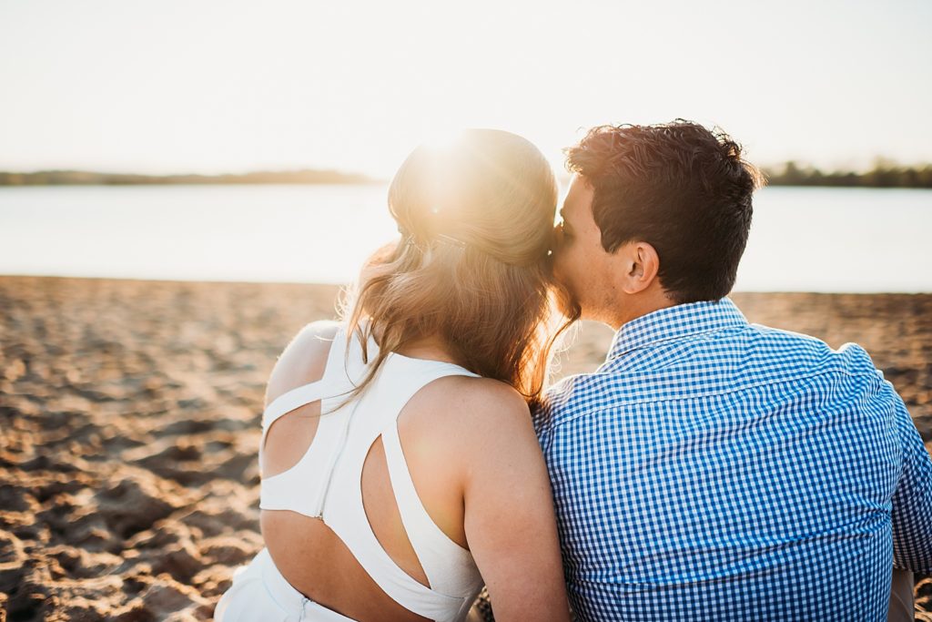 Engaged couple watching the sunset sitting on the beach at stony Creek metro park engagement session