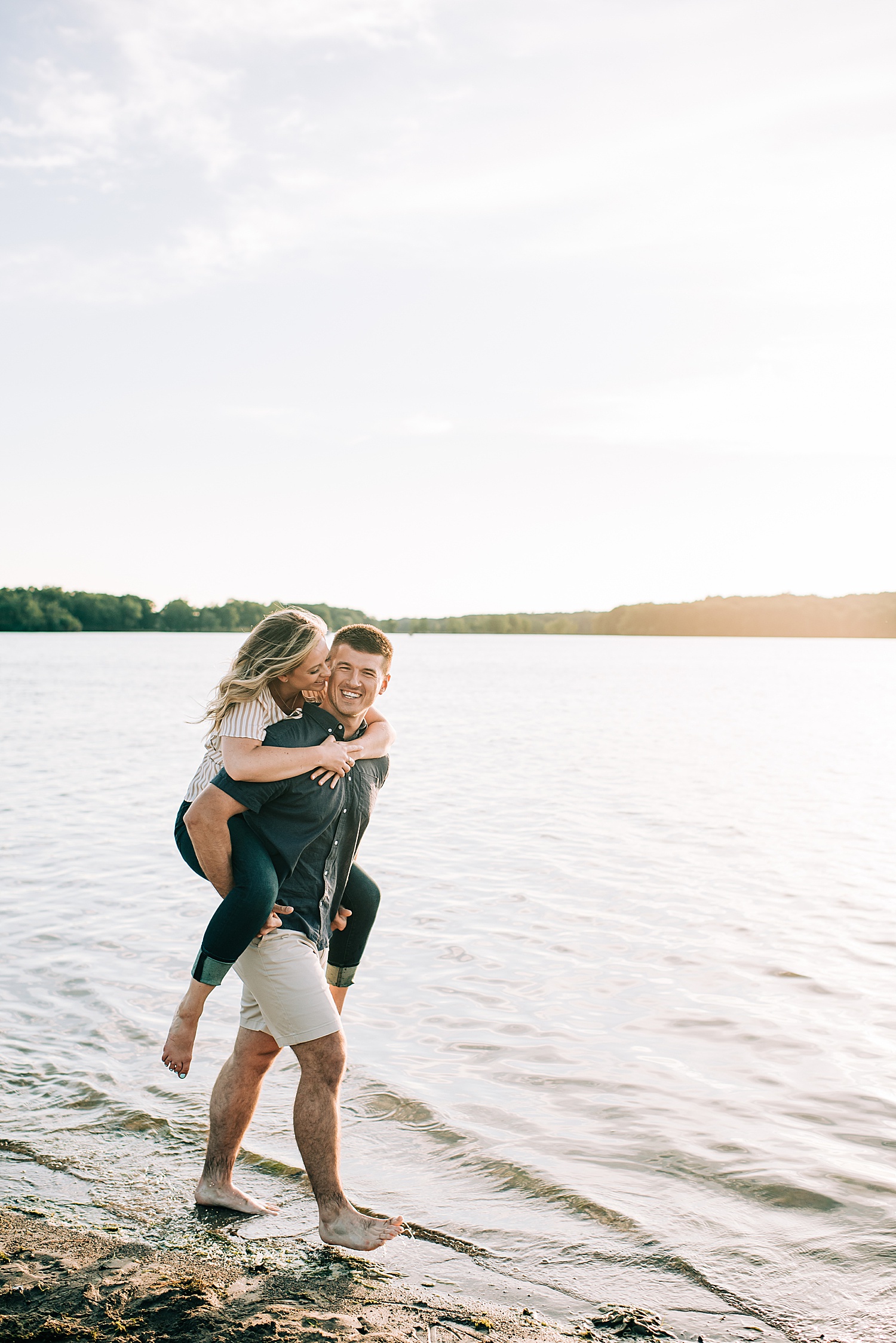 man walks barefoot in water with fiancé during Milford engagement session 