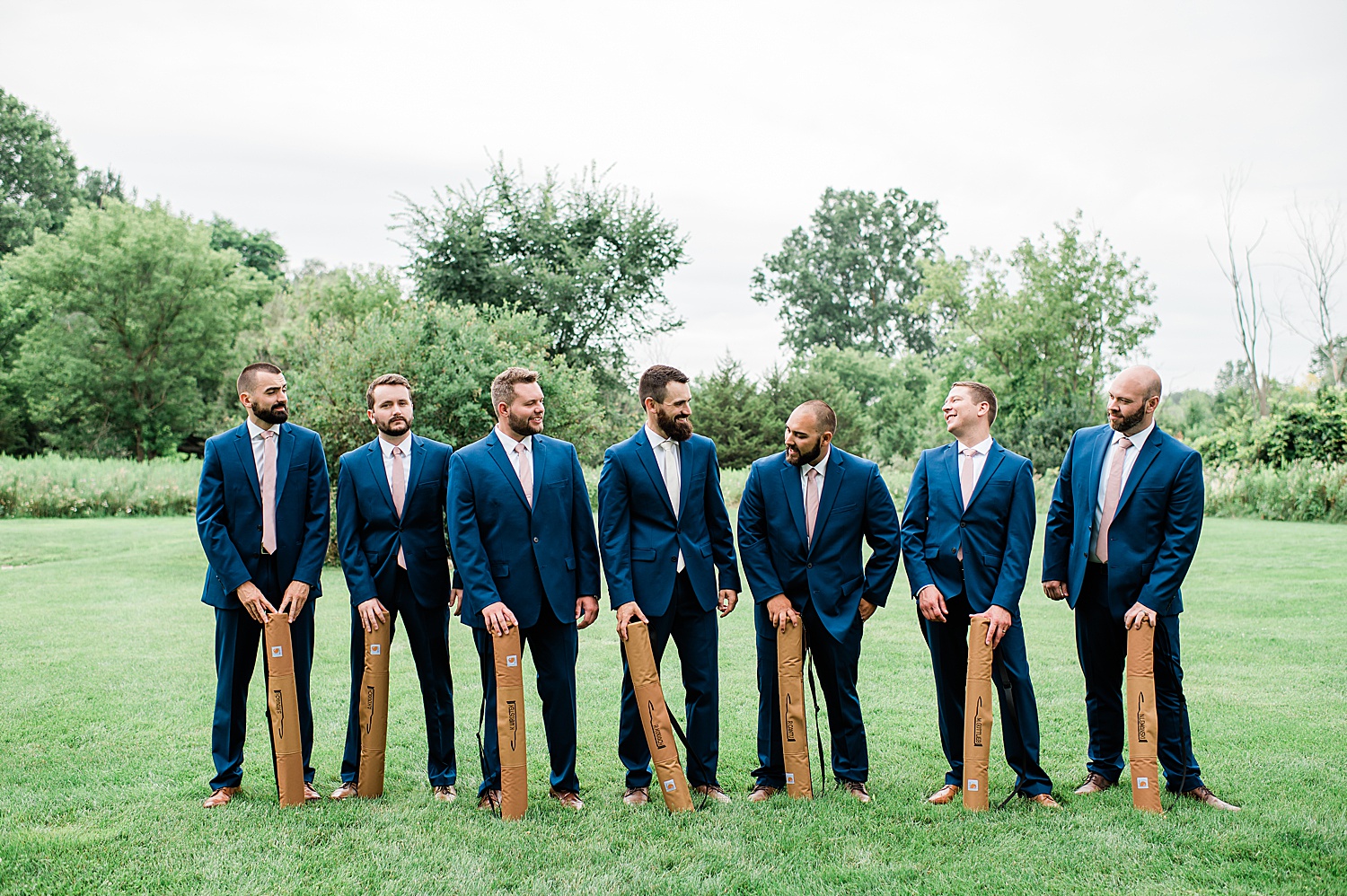 Groomsman holding wedding gifts from bride and groom wearing navy blue suits