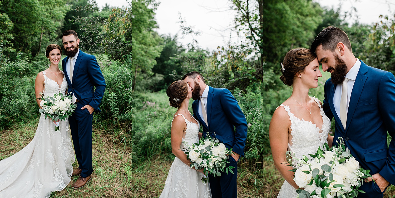 Bride and groom share kiss while holding wedding bouquet with navy blue suit and champagne colored tie