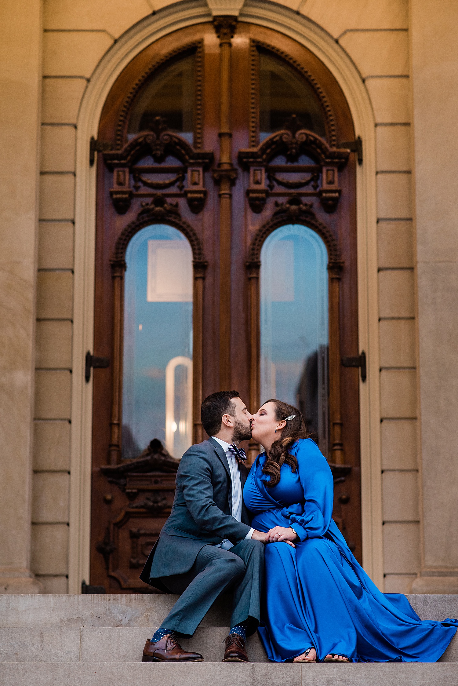 Engaged couple shares kiss in front of wooden doors in Michigan at Lansing engagement session