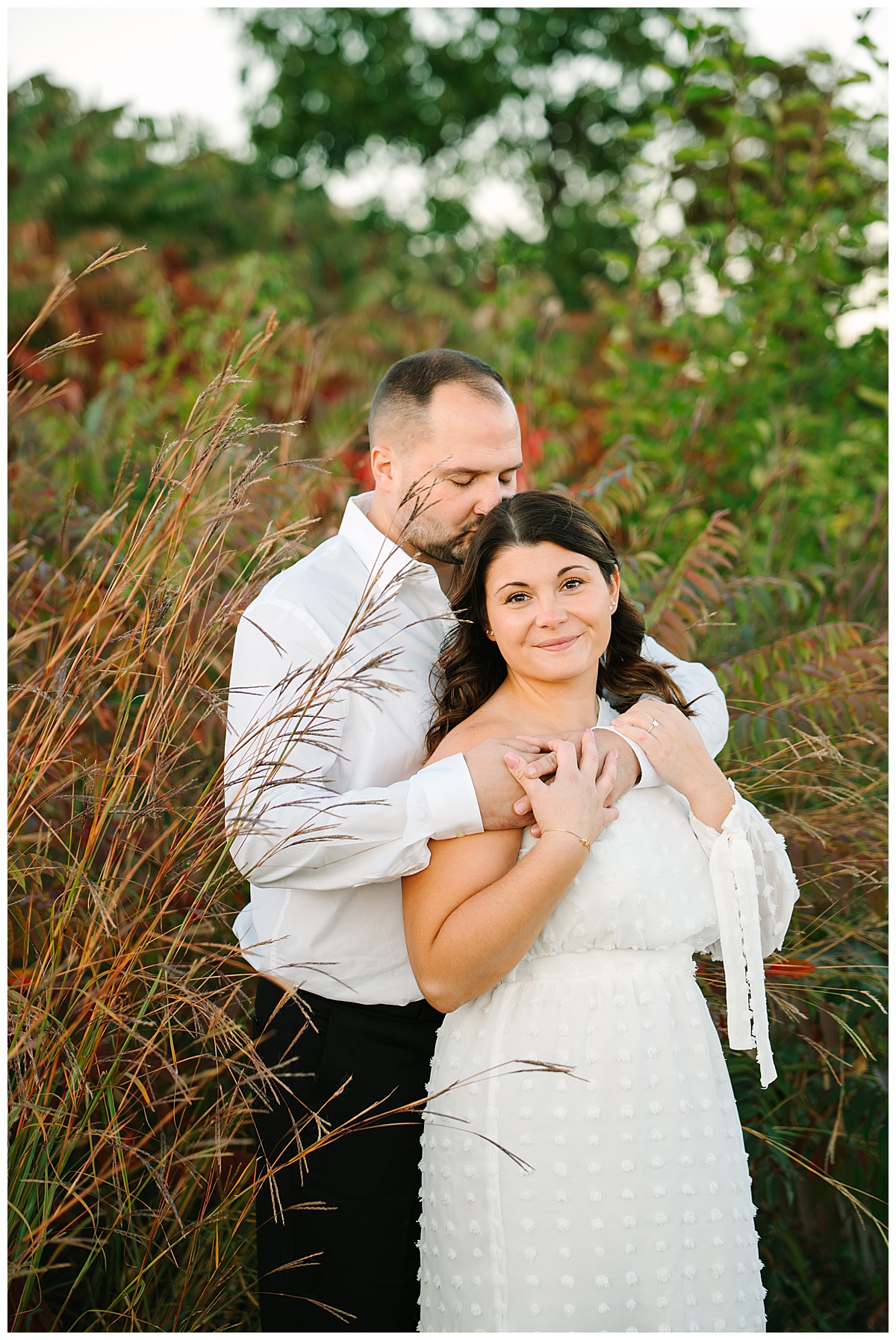 Man kisses woman in front of field for Michigan Wedding Photographer